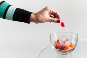 A person picking a candy our of a cnady bowl, these should be avoided due to germs.