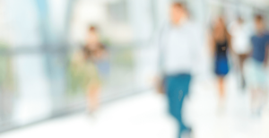 Blurry image of various people walking down hallway.