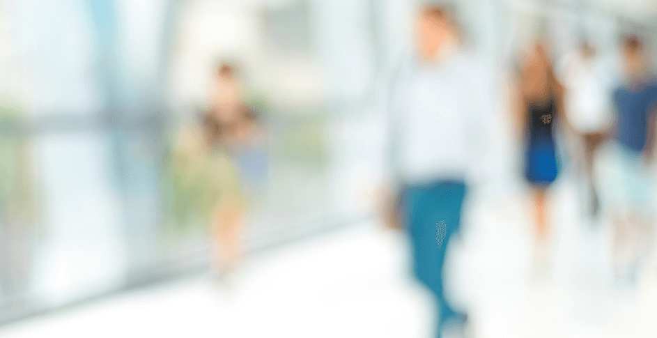 Blurry image of various people walking down hallway.