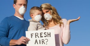 Family Standing with a sign reading Fresh Air? Dirty air is air pollution and affects infection rates of diseases.