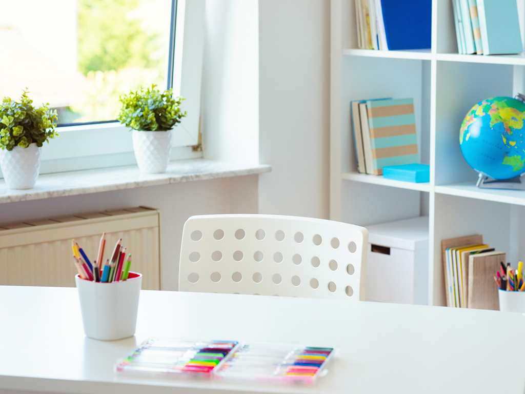 Interior of child’s desk and colored pencils on it and shelf with books; plants could easily add to poor IAQ if the wrong ones are chosen.