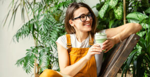 Woman in a chair smiling with plants behind her, Air purification by plants would take so many individual plants that she would not be able to sit in the room.