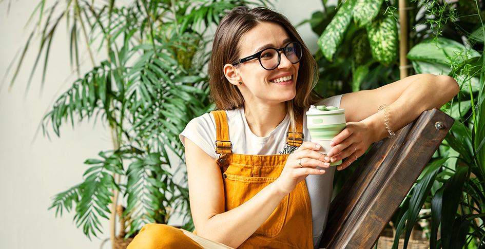Woman in a chair smiling with plants behind her, Air purification by plants would take so many individual plants that she would not be able to sit in the room.