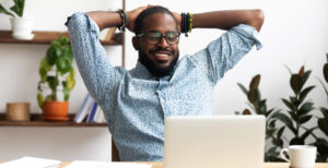Man sitting behind his laptop smiling with financial documents. You can be happy as well, knowing that you budgeted for indoor air quality solutions which help your facility by adding protection for your most important assets.