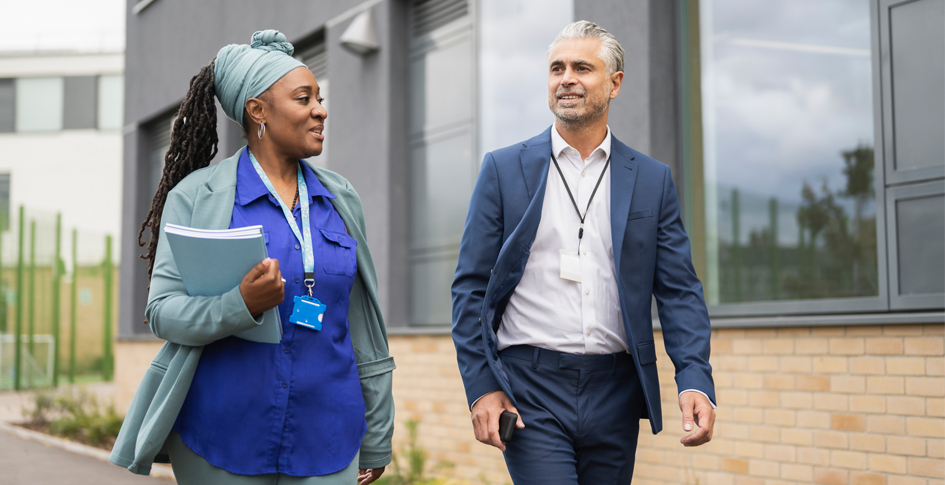 School administrators walking next to each other on campus; school administrators need to recognize factors affecting IAQ and establish a plan to correct poor air quality.