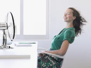 Woman sitting in chair with fan turned on indoors