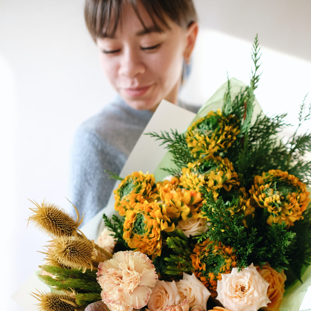 woman holding flowers indoors which introduces allergens into the air, which is reason to choose an ir purifier.