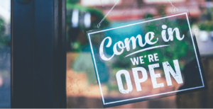 Come in we're open sign on a door of a store front after reopening from Covid.