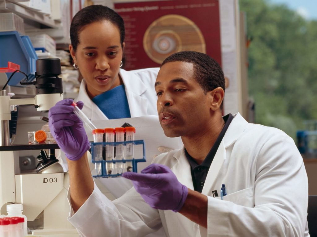 Two scientists conducting Indoor Air Quality Testing in a lab, looking at test tubes with samples