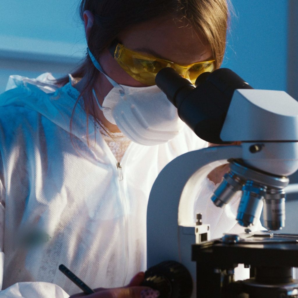 Scientist looking through microscope while analyzing samples that were taken to test indoor air quality